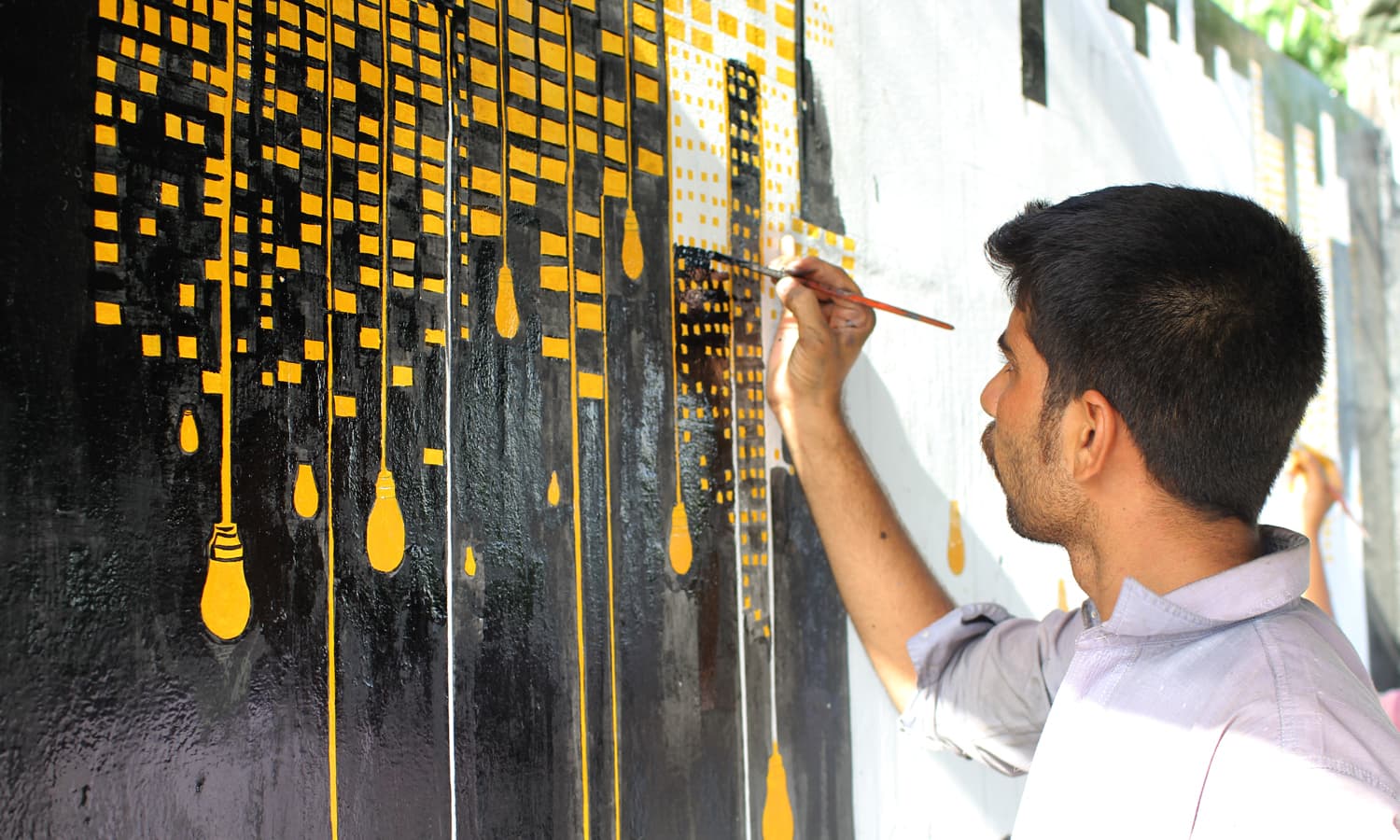 A student painting the wall at MT Khan Road, Karachi