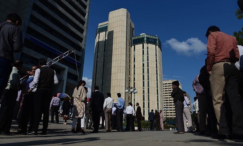 Pakistani federal employees gather outside their offices after a 7.5-magnitude earthquake. -AFP